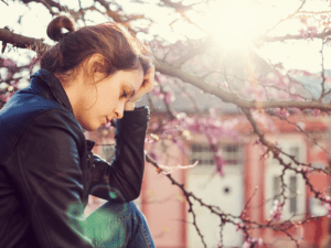A woman sitting outside experiencing symptoms of depression