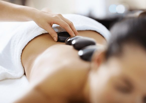 A woman having a hot stone massage in her home