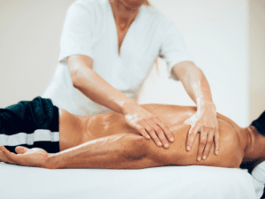 A man receiving a sports massage at his home in Los Angeles from a sports massage therapist
