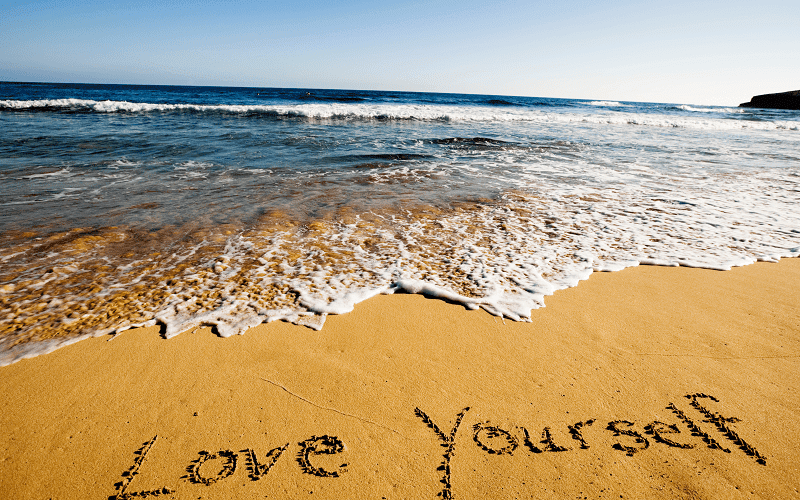 A picture of love your self written in the sand at a beach Los Angeles