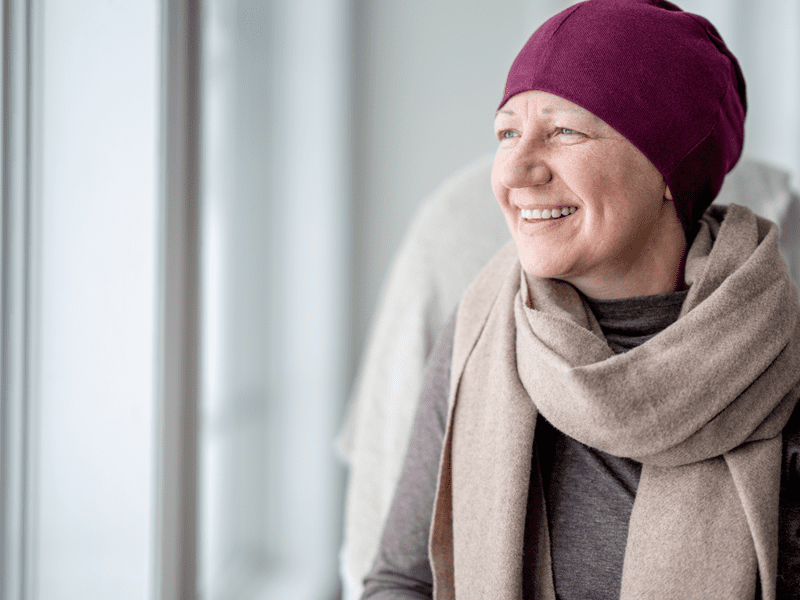 A cancer patient staring out a window with a smile on her face after receiving an oncology massage